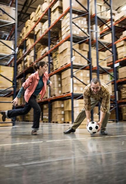 Dois trabalhadores de armazém jogando futebol durante uma pausa de