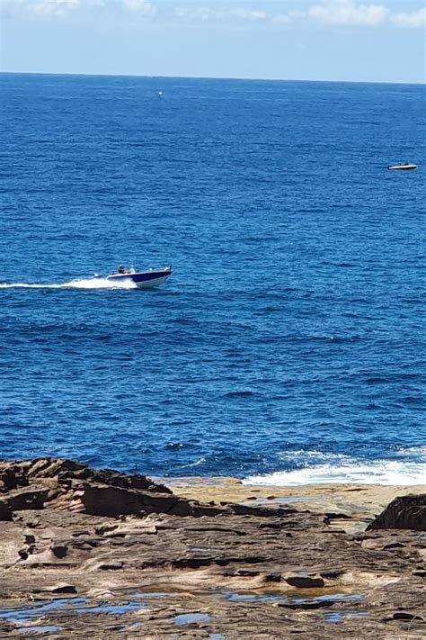 A Boat Is Out On The Water Near Some Rocks