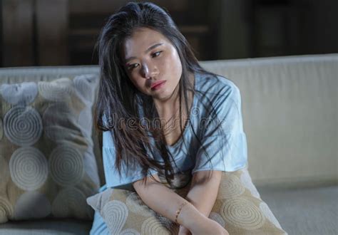 Young Beautiful Sad And Depressed Asian Japanese Woman At Home Sofa