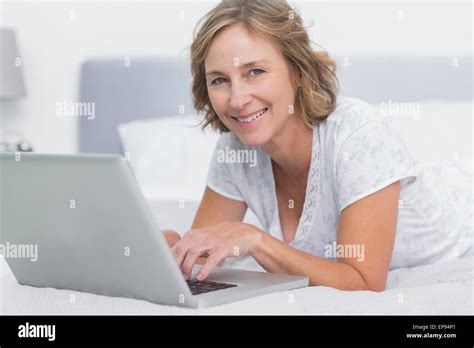 Smiling Blonde Woman Lying On Bed Using Laptop Stock Photo Alamy