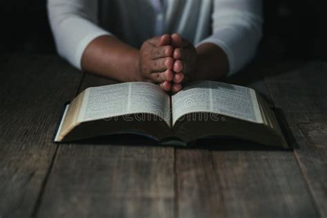 Hands Folded In Prayer On A Holy Bible In Church Concept For Faith