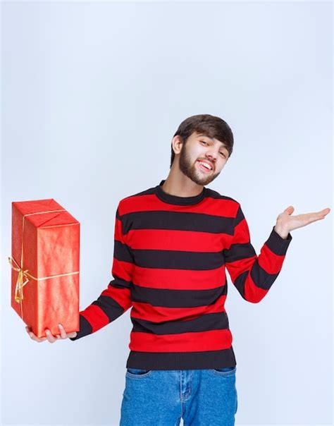 Hombre De Camisa A Rayas Rojas Sosteniendo Una Caja De Regalo Roja Y