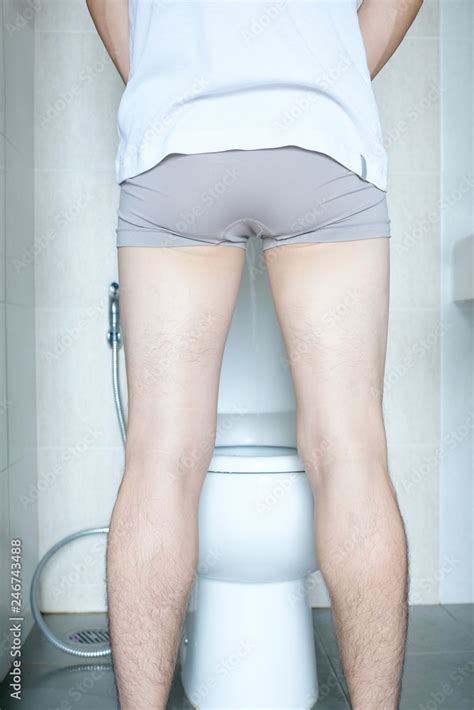 Rear View Leg Of Man Standing Peeing To Toilet Bowl In Restroom At Home