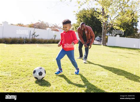 Happy African American Father And Son Playing Football In Their