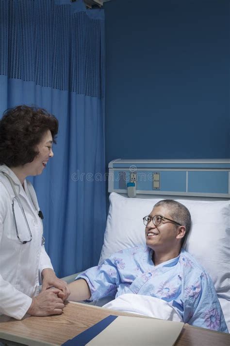 Smiling Doctor Checking Up On A Patient Lying Down In A Hospital Bed