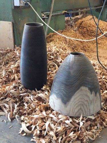 Two Black Vases Sitting On Top Of Wood Shaving In A Pile Of Mulch