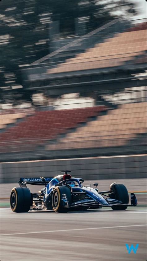 a blue race car driving on a track in front of an empty bleachers