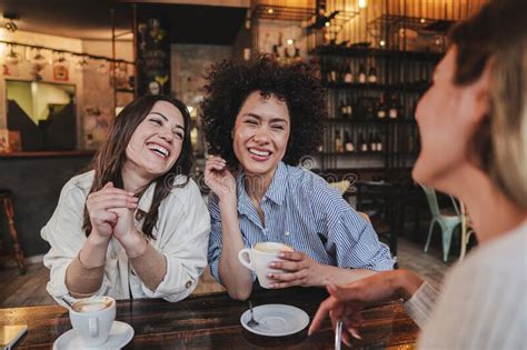 A Group Of Young Women Talking And Laughing Sitting On A Coffee Shop Or