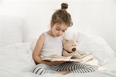 Cute Little Girl Reading a Book on the Bed in the Bedroom Stock Image - Image of happy, book ...