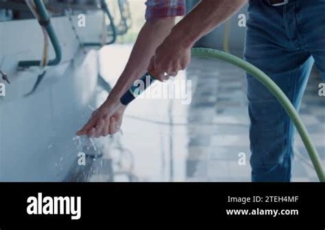 Farmer Washing Hands Working With Milking Device Using Hose On Automated Dairy Manufacture Farm