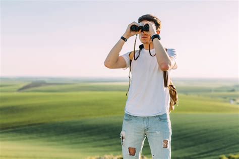 Un Jeune Homme Regardant à Travers Les Jumelles Contre Les Terres