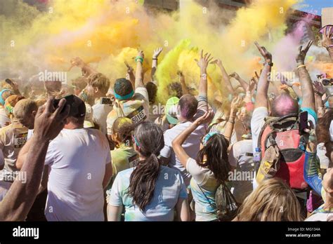 A Large Crowd Of Runners Who Completed The Color Run Toss Packets Of