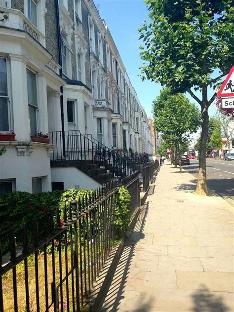 An Empty Sidewalk In Front Of Some White Buildings With Black Railings