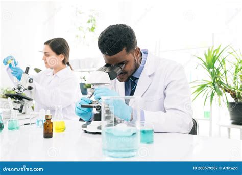 Young African Black Man Scientist Looking Through A Microscope In A