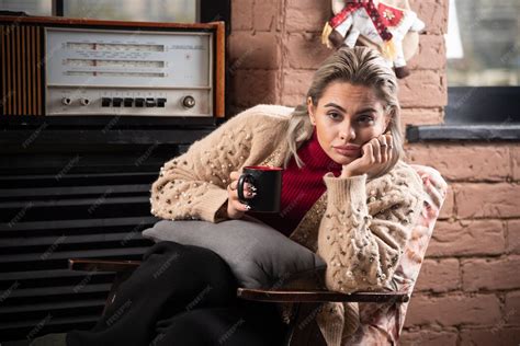 Mulher pensativa sentada, lendo um livro e tomando café | Foto Grátis