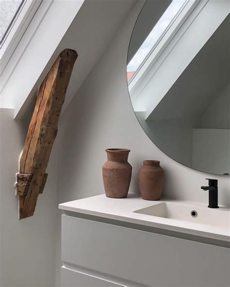 A White Bathroom With Two Vases On The Counter And A Mirror Over The Sink