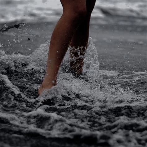 A Person Standing In The Water With Their Legs Up And Feet Down While