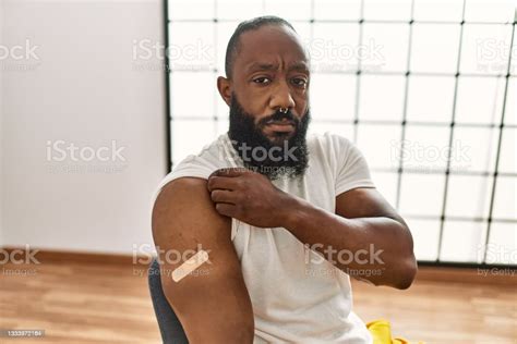 African American Man Getting Vaccine Showing Arm With Band Aid Thinking