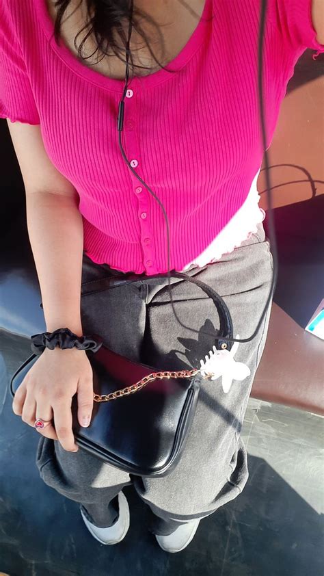 A Woman In Pink Shirt Holding A Black Purse