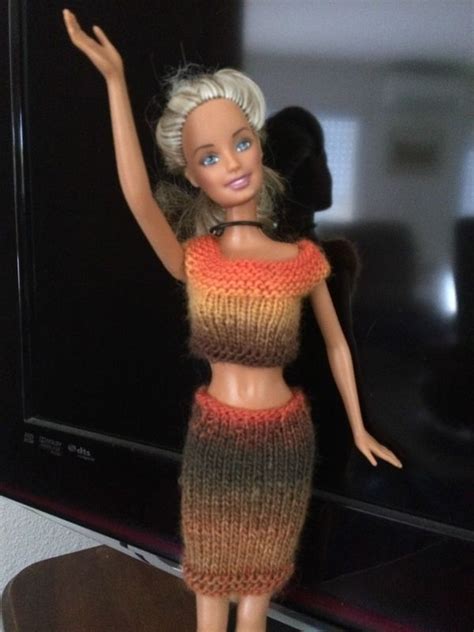 A Barbie Doll Wearing A Knitted Dress And Holding Her Arm Up In The Air