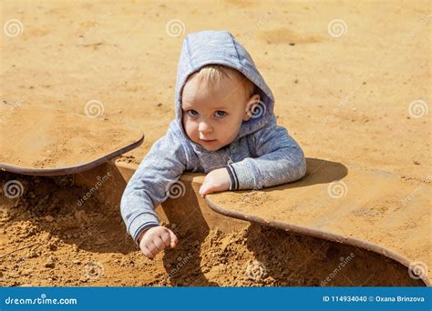 Cute Toddler Playing On The Playground In The Sandbox In Spring Sunny