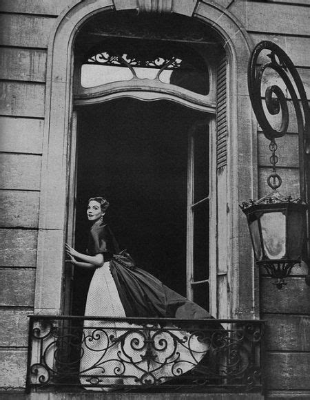 A Woman In A Dress Standing On The Balcony Of A Building With An Open