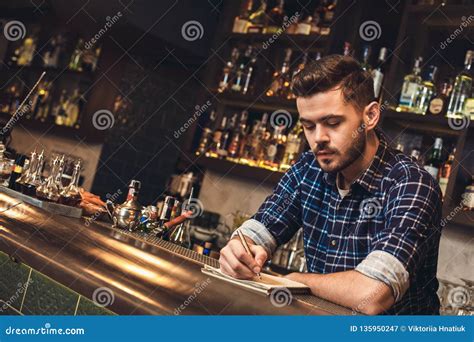 Young Bartender Leaning On Bar Counter Taking Notes Concentrated Stock