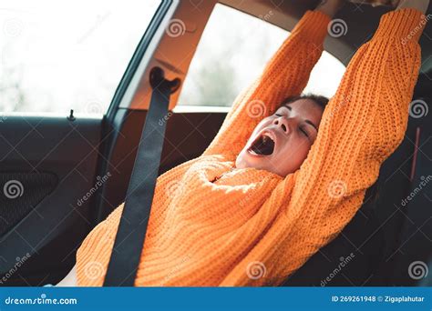 Caucasian Woman Yawning In The Car Stretching Her Arms Out Wearing A