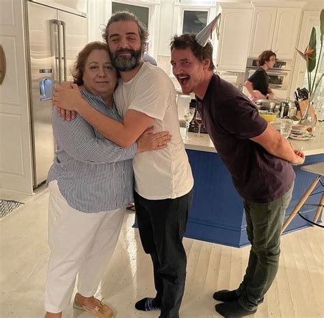 Two Men And A Woman Hug In The Kitchen While Standing Next To Each