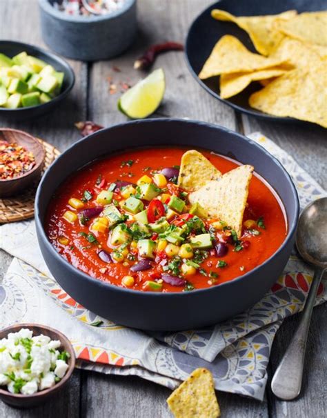 Sopa mexicana de tomate y pimiento en tazón negro con chips de nachos