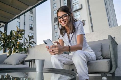 Sorrindo jovem latina carregando histórias para suas redes sociais sentado no terraço de um