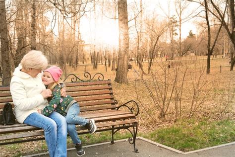 Grandmother With Her Granddaughter Hugging And Talking Sitting On A