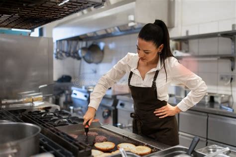 Professional Female Chef Preparing Meal Indoors In Restaurant Kitchen