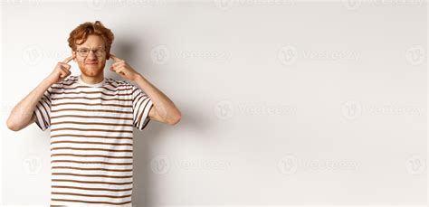 Annoyed young man complaining on loud noise, shut ears and grimacing