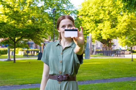 Jonge Blonde Meid In Een Groene Jurk Met Een Creditcard Op Een Parkachtergrond Stock Afbeelding