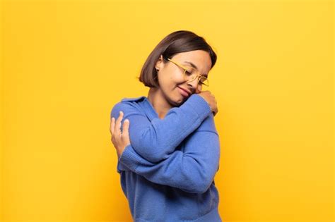 Joven mujer latina que se siente enamorada sonriendo abrazándose y