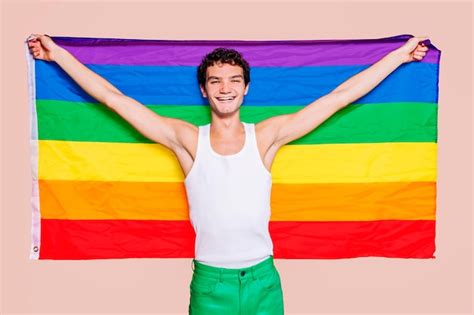 Premium Photo Cheerful Gay Boy Holding Rainbow Flag At Studio