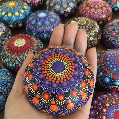 a hand is holding a painted rock in front of many other rocks