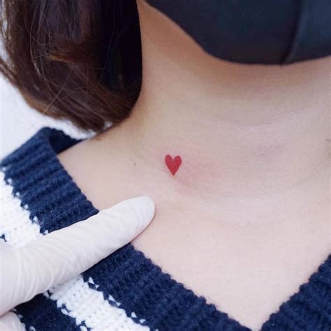 Minimalist red heart tattoo on the neck.