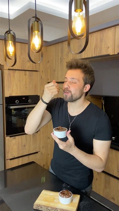 A Man Is Eating In His Kitchen While Drinking From A Cup And Looking Up