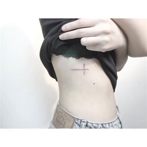 Word "miracles" in the shape of a cross tattooed on the