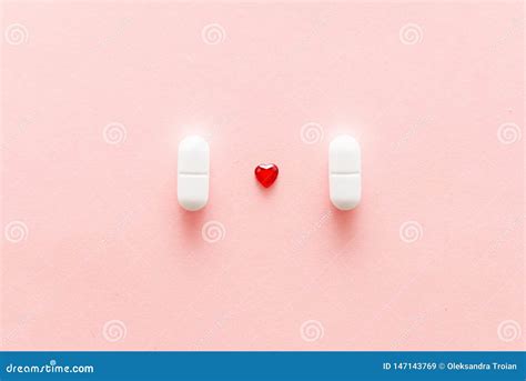 Two White Pills On Pink Background With Red Heart Shape Cardiac