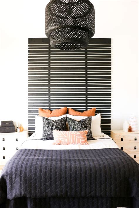 A Black And White Bed With Orange Pillows On Its Headboard In A Bedroom