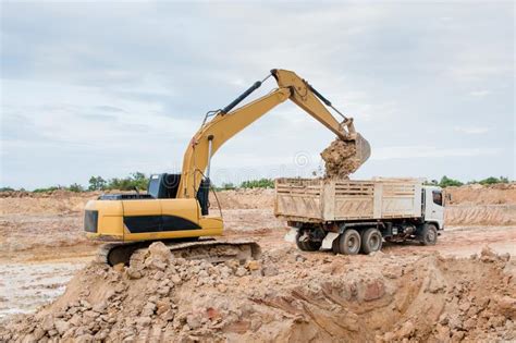 Yellow Excavator Machine Loading Soil Into A Dump Truck At Construction