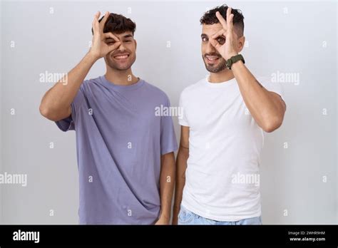 Homosexual Gay Couple Standing Over White Background Doing Ok Gesture With Hand Smiling Eye