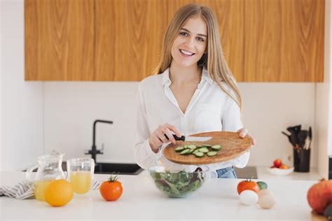 Premium Photo A Happy Cute Blonde Woman Is Preparing A Salad In The