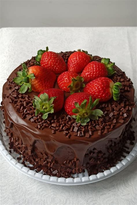 A Chocolate Cake Topped With Strawberries On Top Of A White Tablecloth