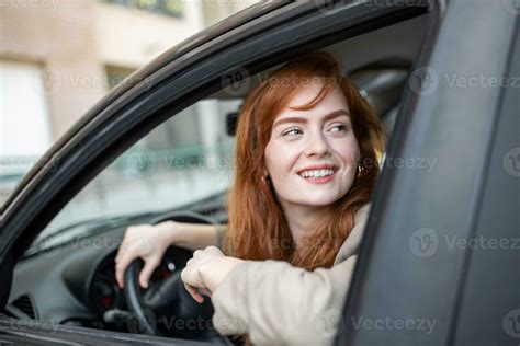 Joyful Redhead Woman Inside Of Car Looking Back From Driver Seat While Driving During The Day