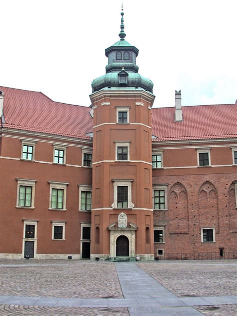 An Old Brick Building With A Clock Tower On The Top And Red Tile Flooring