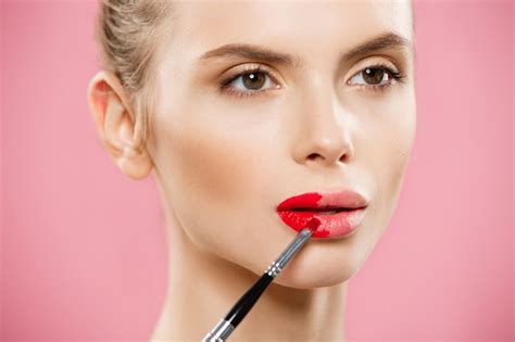 Premium Photo Woman Applying Lipstick Over Pink Background